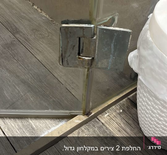 ציר דלת זכוכית במקלחת על רצפת עץ